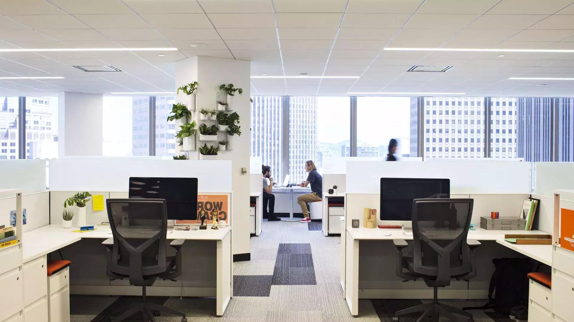 贝博体彩app办公楼的内部场景, 两个人在大窗户前的一张桌子上工作.