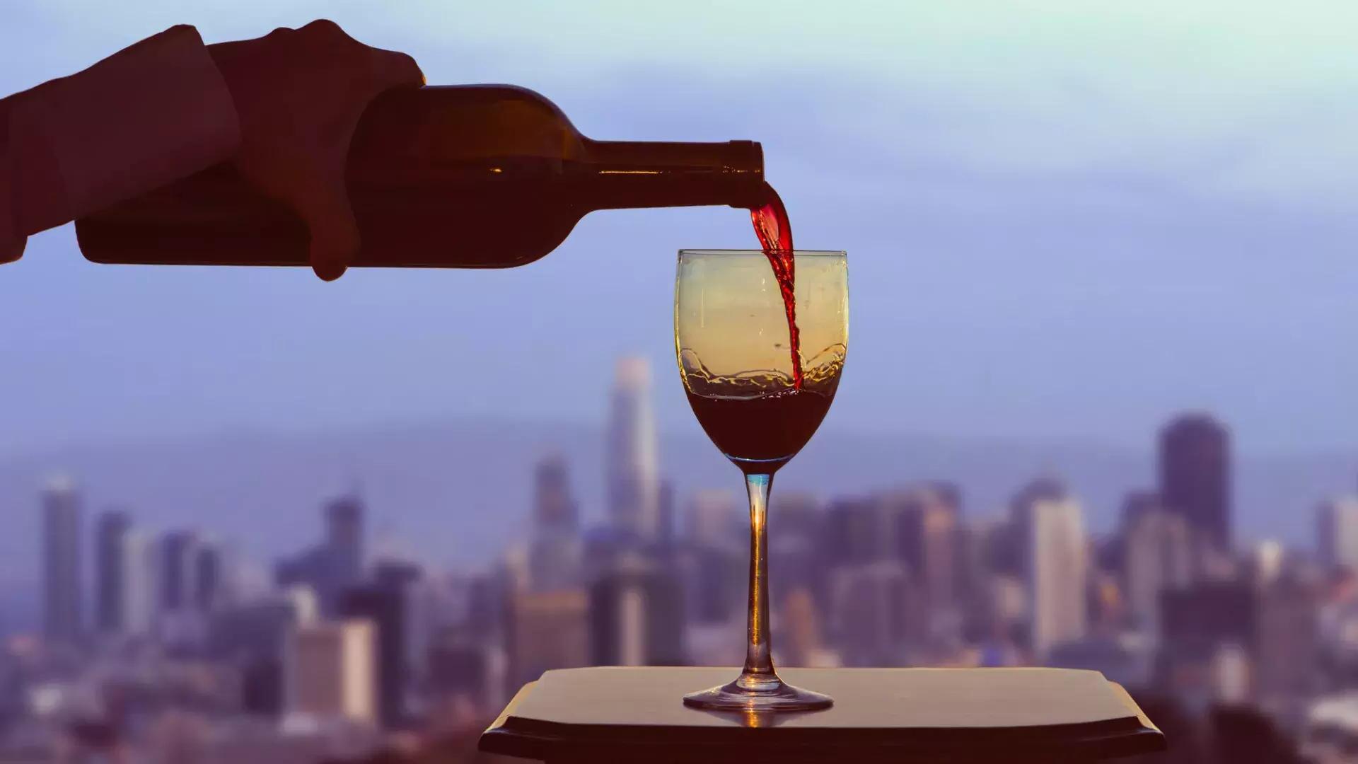 Se sirve una copa de vino tinto, con el horizonte de 贝博体彩app visible desde la ventana.