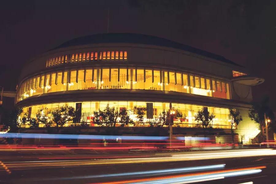 路易丝M的外观. Davies Symphony Hall à noite com raios de luz dos veículos que passam.