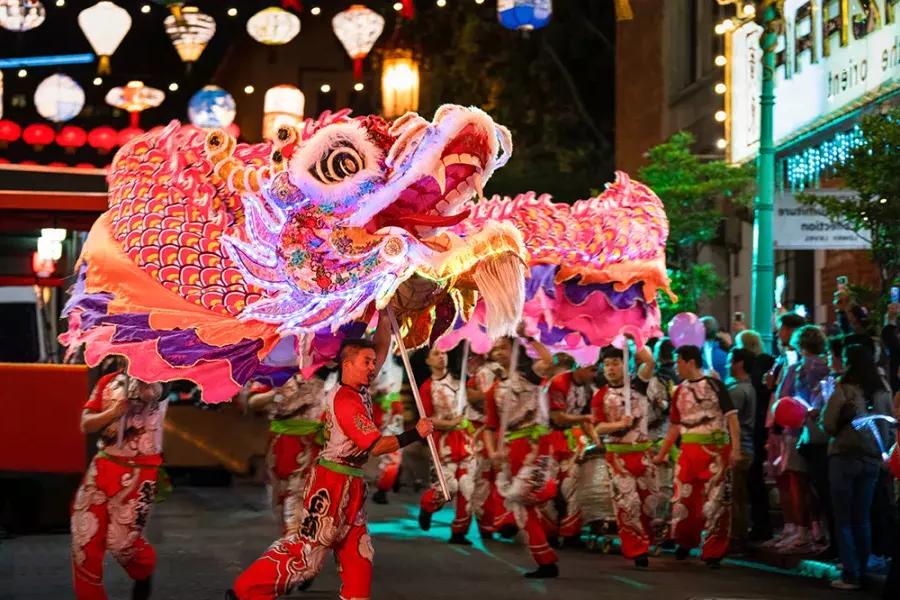 舞者在贝博体彩app农历新年游行中操纵一个巨大的物体, beleuchteten Drachen.