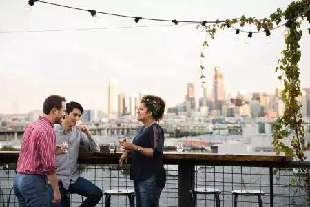 Three people gather around an outdoor table on the roof deck of Anchor Distilling in 加州贝博体彩app.