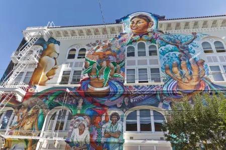 一幅丰富多彩的，大规模的壁画覆盖了贝博体彩appmission distric女性大厦的侧面.
